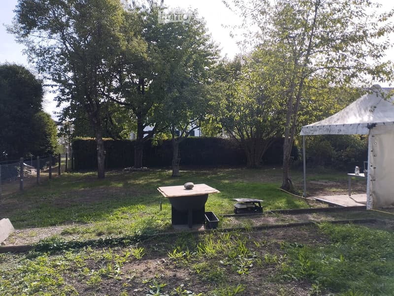 Garden with a barbecue, a small table, a tent, and several trees providing shade.