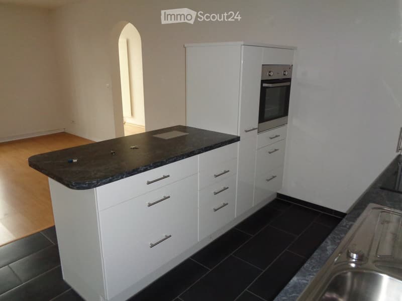 Modern kitchen with white cabinets, dark granite countertop, stainless steel sink, and built-in oven.