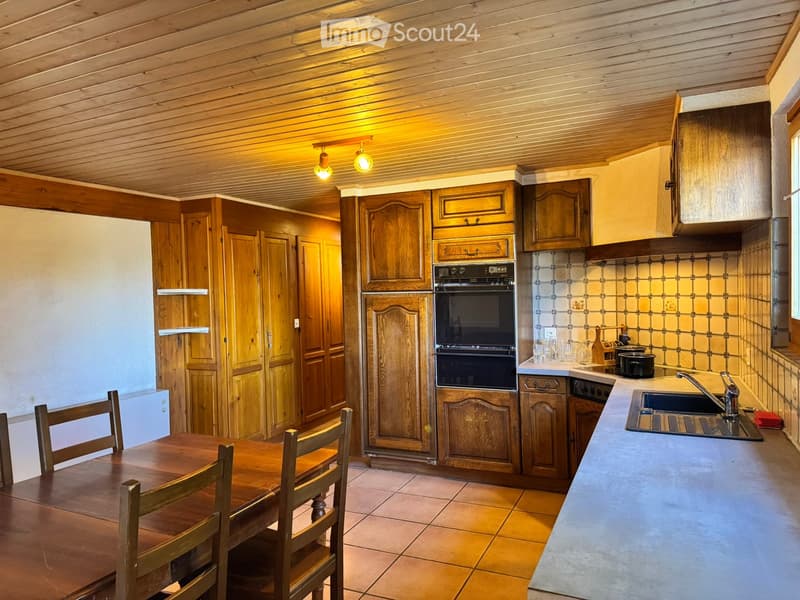 Cozy kitchen with wooden cabinets, an oven, a sink, and a small dining area with a table and chairs.