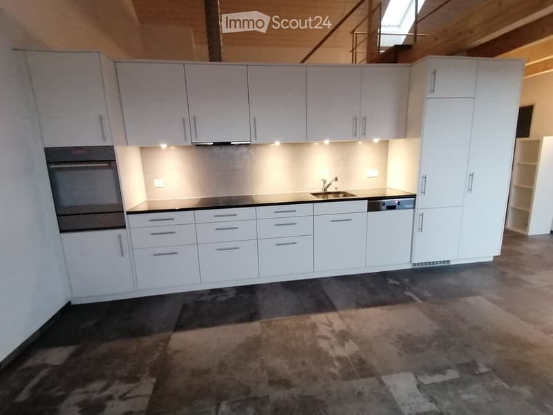 Modern kitchen with white cabinets, stainless steel appliances, and a dark countertop.