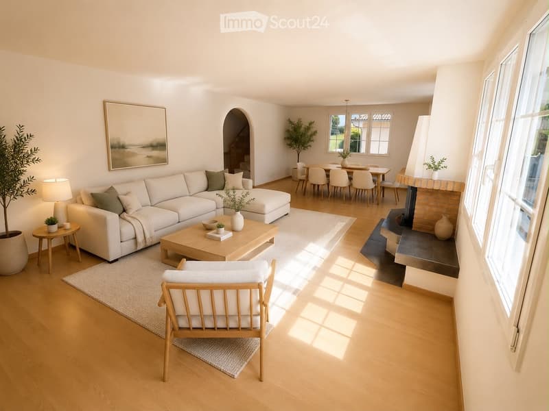 Bright living room with white walls, wooden flooring, a white sectional sofa, coffee table, armchair, fireplace, and dining area visible in the background.
