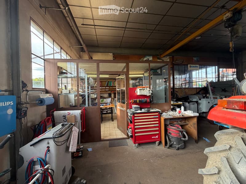 Workshop with large windows, tool chest, shelves, vacuum cleaner, and various equipment.