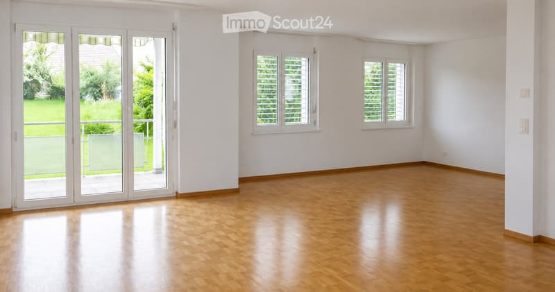 Empty room with wooden flooring, white walls, large sliding glass doors leading to a balcony, and two windows with blinds.