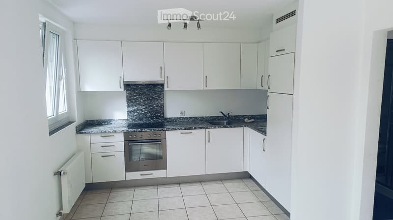 Modern kitchen with white cabinets, granite countertop, stainless steel oven, and sink.