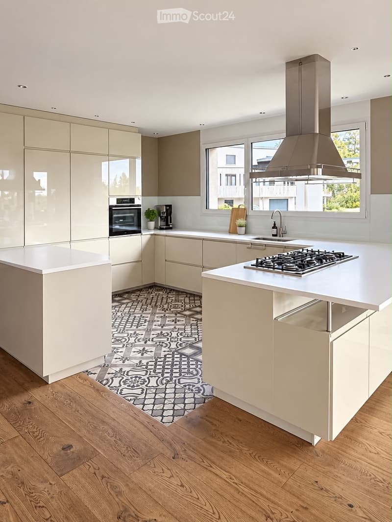 Modern kitchen with light-colored cabinets, white countertops, a gas stove, and a large range hood. Features a central island, wooden flooring, and a decorative tile backsplash.