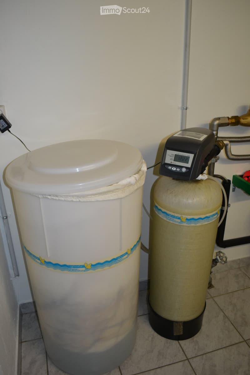 Water softener and water tank in a utility area, with digital display and control panel.