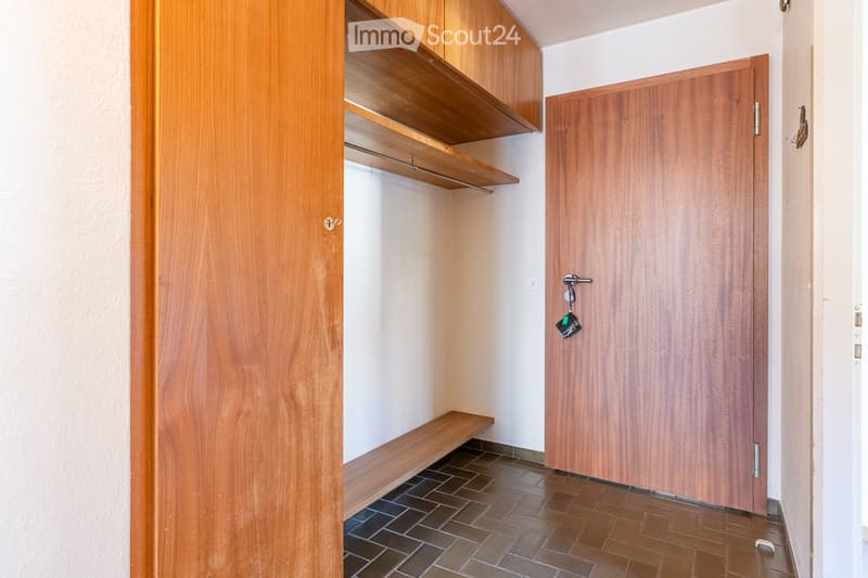 Empty hallway with wooden doors, built-in wooden shelves, and tiled floor.