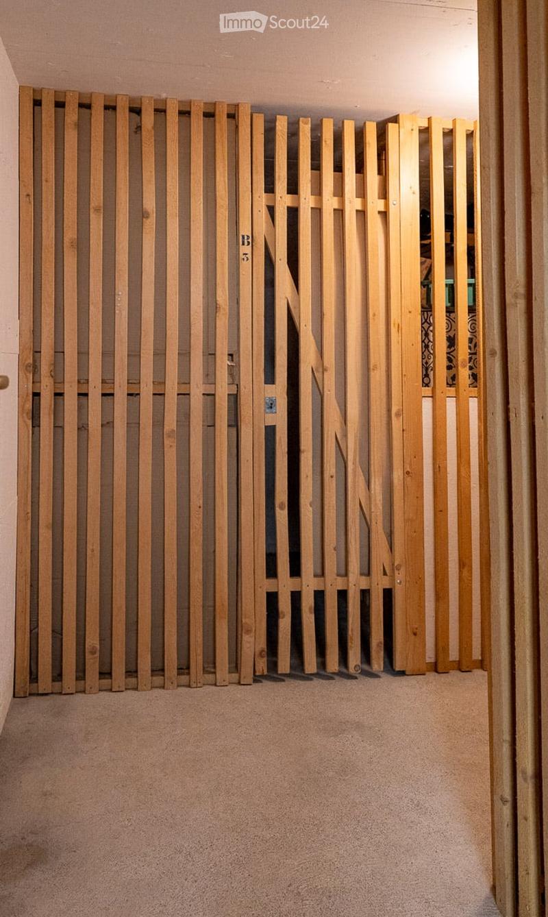 A narrow hallway with a wooden slatted partition on one side, carpeted floor, and visible room numbers on the partition.