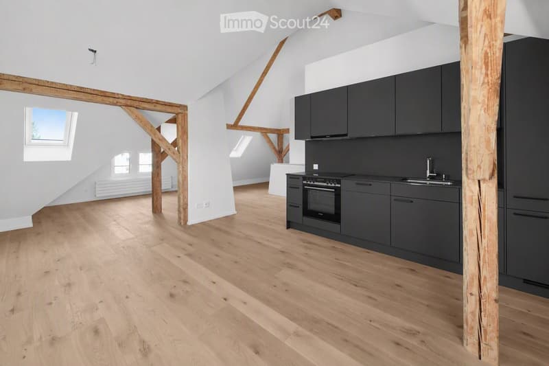 Modern kitchen with dark grey cabinets, a built-in oven, and a sink, featuring light wooden flooring and exposed wooden beams.