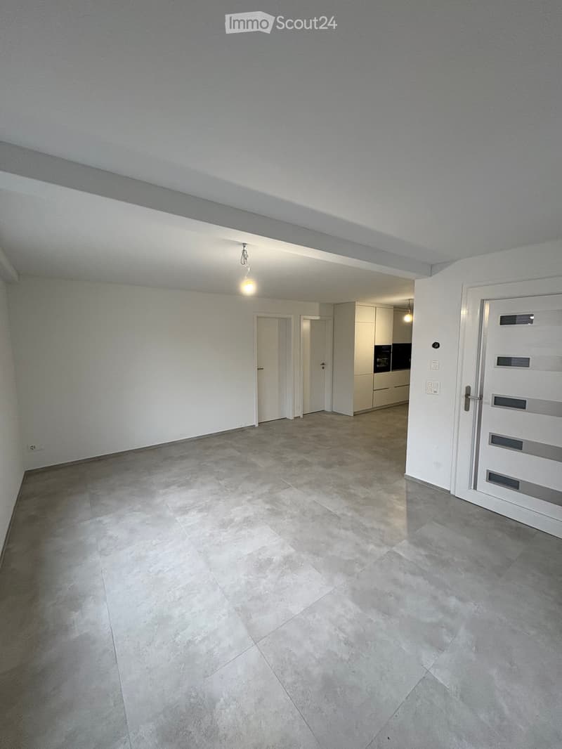 Empty room with light grey walls, tiled floor, and white doors leading to other spaces. No furniture or equipment visible.