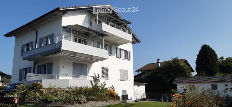 2 story house, white exterior, multiple balconies, garden, car parked in front