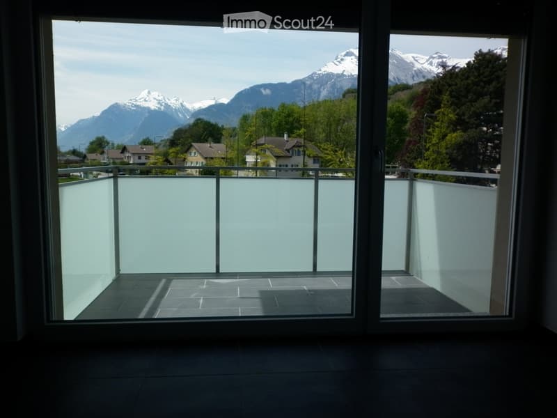 Balcony with modern glass railing, tiled floor, and scenic mountain view.