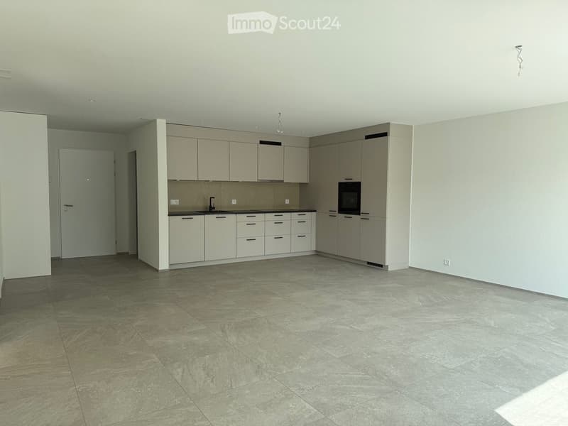 Empty kitchen with light-colored cabinets, a sink, and tiled flooring.