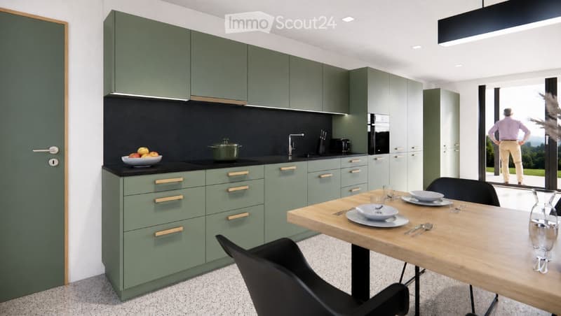 Modern kitchen with green cabinets, black countertops, and a wooden dining table with chairs. A bowl of fruit and a pot are on the counter, and a person is seen through a large window.