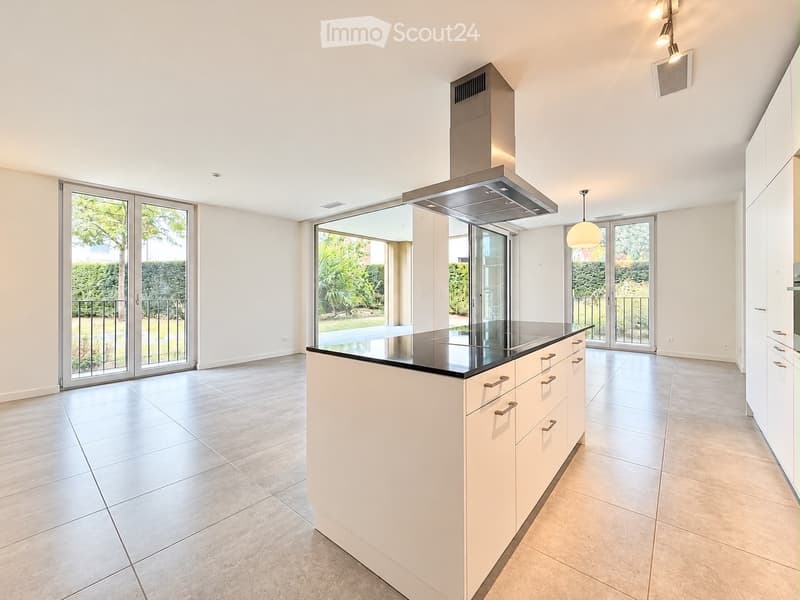 Modern kitchen with white cabinets, a central island, and large glass doors leading to a garden.