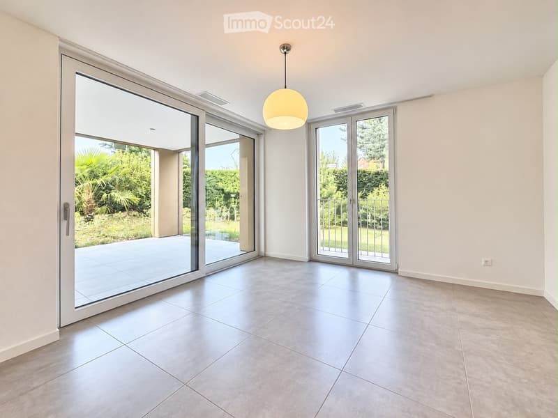 Empty room with large sliding glass doors leading to a patio, tiled floor, and a hanging light fixture.