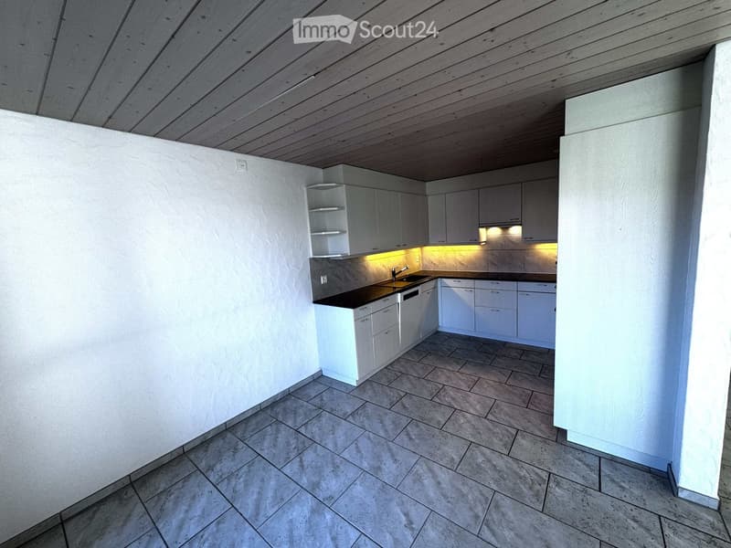 Modern kitchen with white cabinets, a black countertop, and built-in lighting. The space features a tiled floor and a sleek, minimalist design.