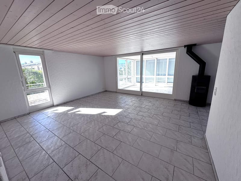 Empty room with tiled floor, white walls, large windows, and a fireplace in the corner.