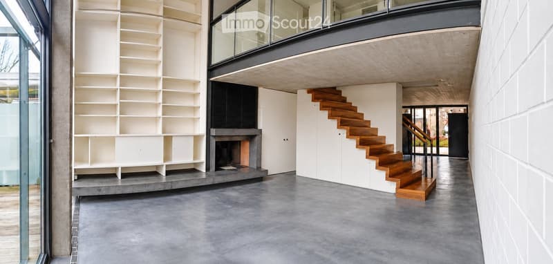Modern hallway with concrete floors, white walls, built-in shelving, wooden staircase, and a fireplace.
