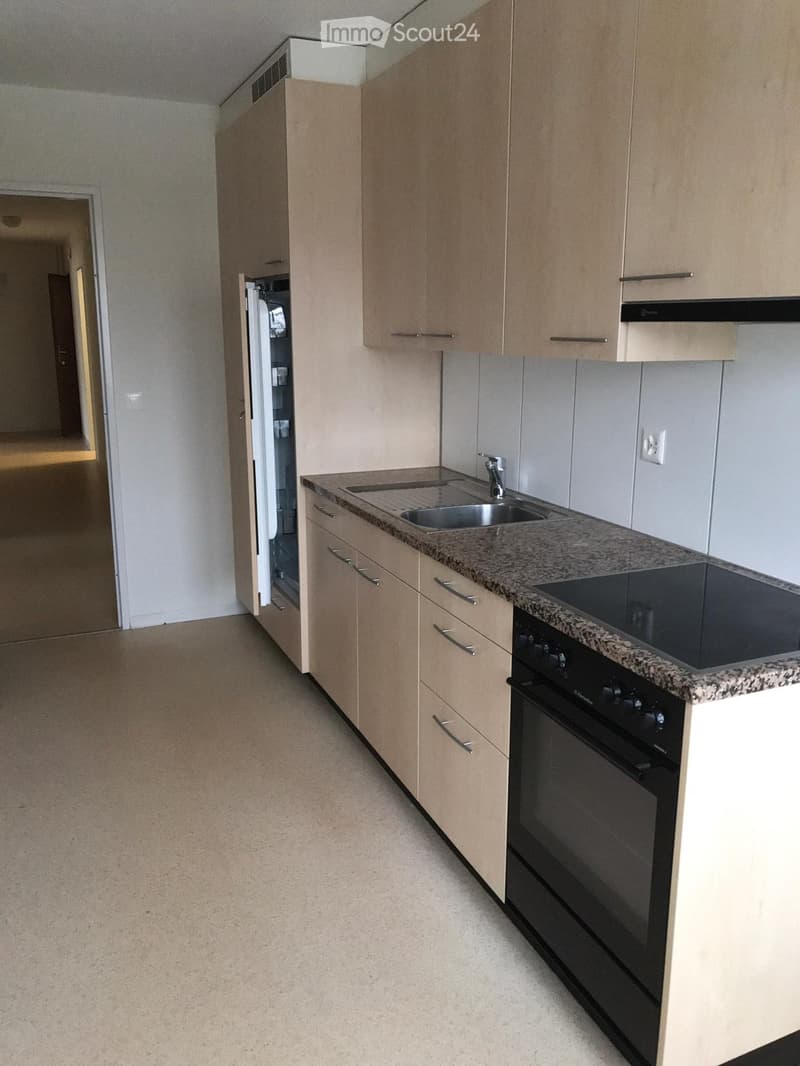 Modern kitchen with light wood cabinets, granite countertop, stainless steel sink, and built-in oven.