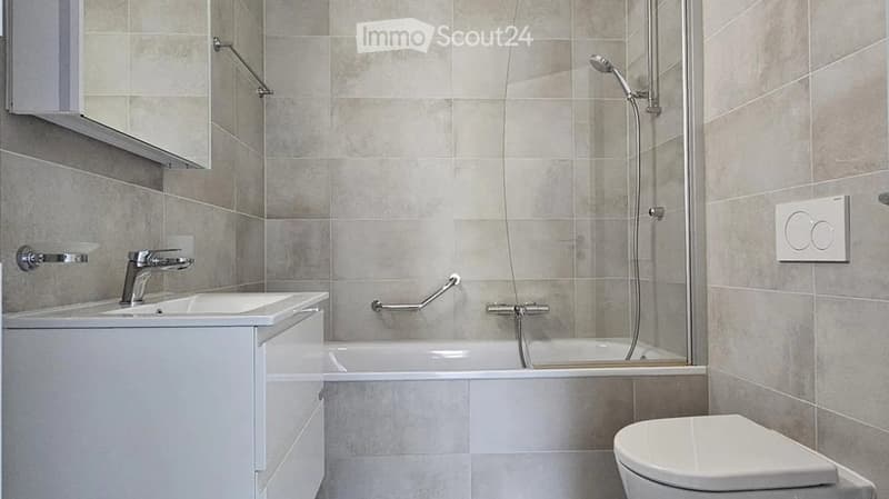 Modern bathroom with a white sink, bathtub, shower, and toilet. Features a glass shower enclosure, modern fixtures, and a sleek design.