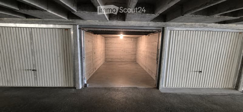 Underground garage with two open doors, concrete walls, and a concrete floor.