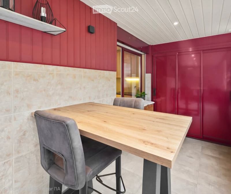 Modern dining area with a wooden table and grey chairs, red cabinets, and a tiled backsplash.