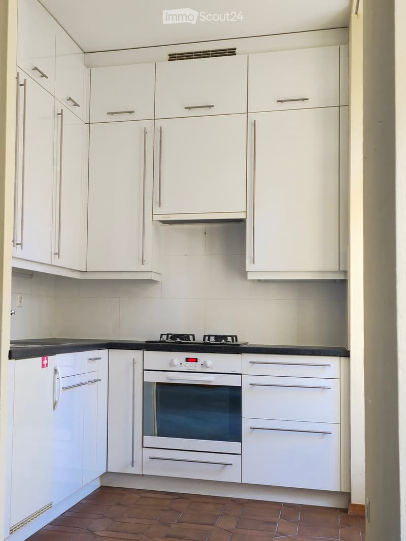 Modern kitchen with white cabinets, stainless steel appliances, and a black countertop.