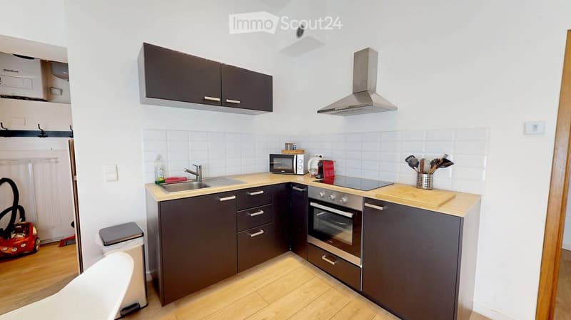 Modern kitchen with dark grey cabinets, stainless steel appliances, a wooden island, and various kitchen utensils.