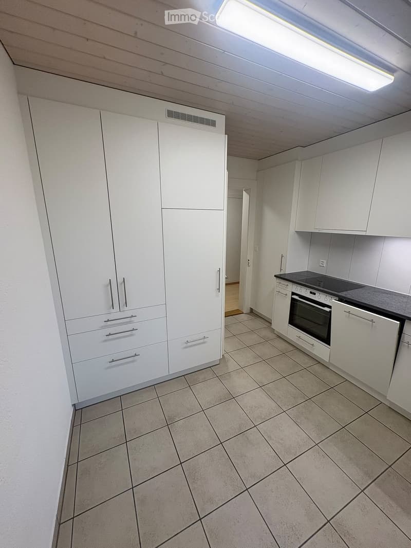 Modern kitchen with white cabinets, tiled floor, and built-in appliances including an oven and stove.