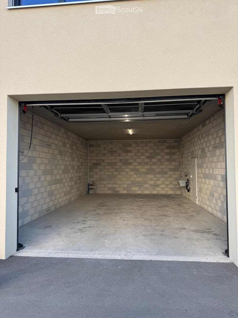 Garage with concrete floor, tiled walls, and a single sink in the corner.