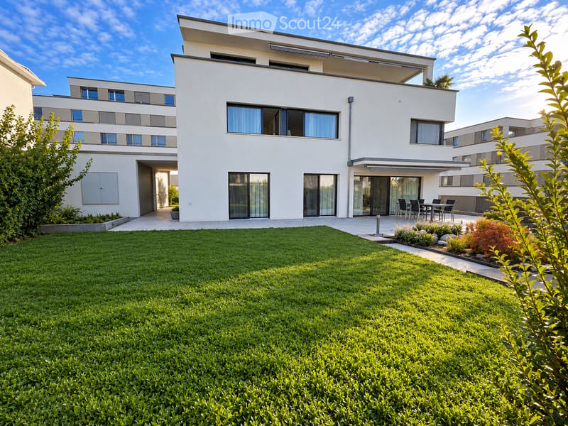 Modern two-story house with white exterior, large windows, and a well-maintained lawn in front.
