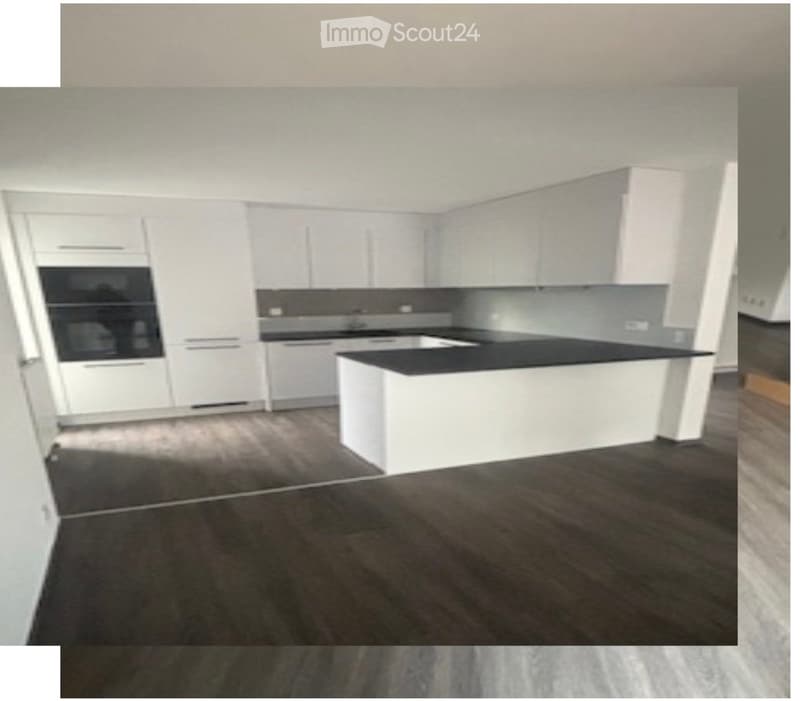 Modern kitchen with white cabinets, black countertop, and built-in oven. Dark wooden flooring.