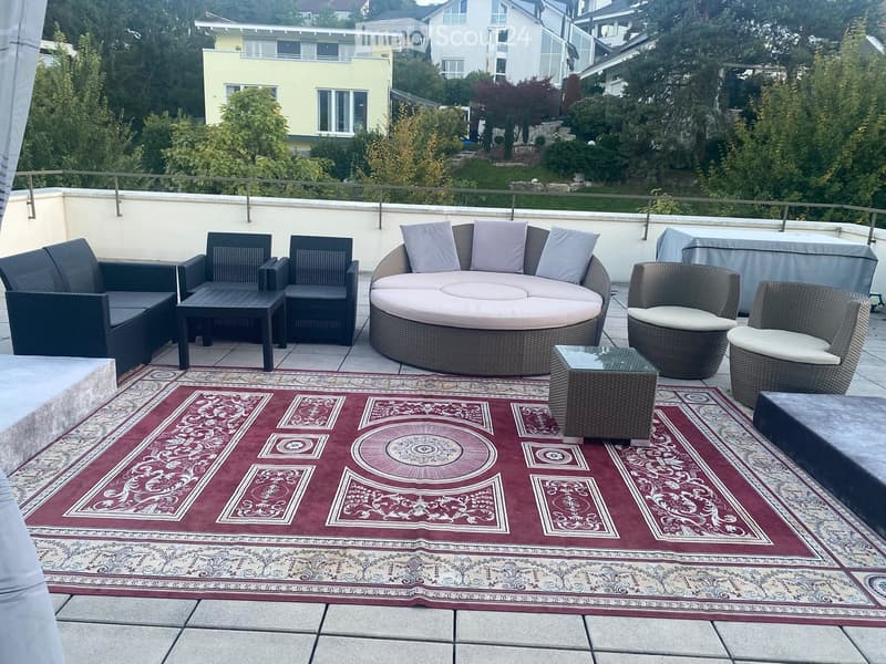 Balcony with a round sofa, several chairs, small tables, and a patterned rug.