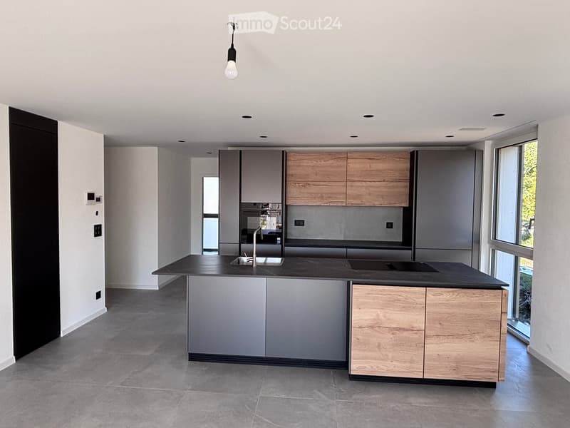 Modern kitchen with grey and wooden cabinets, black countertop, and stainless steel sink.