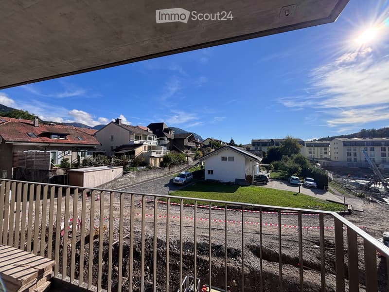 Balcony overlooking a residential area with houses, parked cars, and a construction site below.