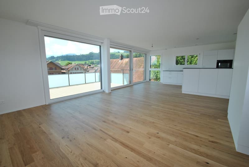 Empty room with wooden flooring, large windows, and a view of the countryside. No furniture or equipment present.