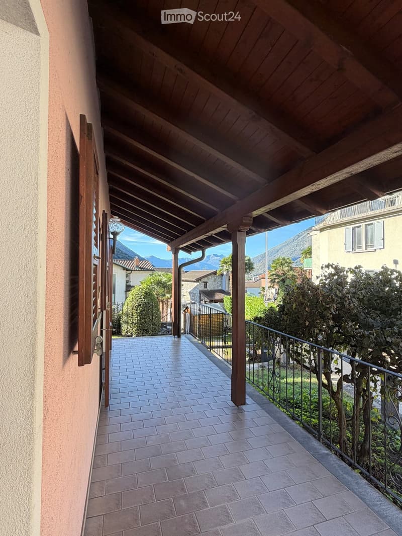 Covered balcony with wooden ceiling, tiled floor, metal railing, and scenic mountain view.