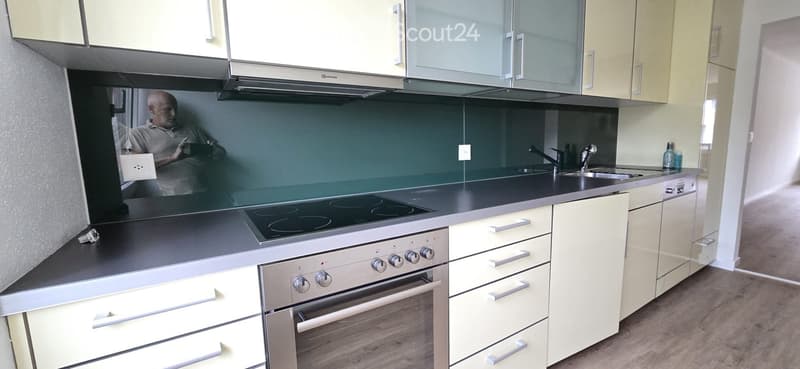 Modern kitchen with light-colored cabinets, stainless steel appliances, and a black countertop.