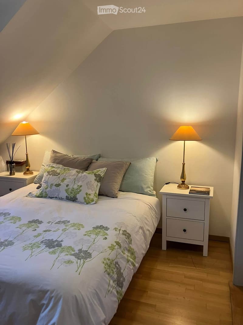 Cozy attic bedroom with a large bed, nightstands, table lamps, and decorative pillows.