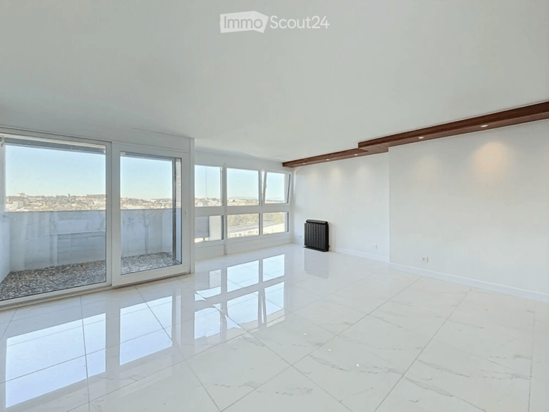 Empty room with white walls, polished white tile flooring, large windows, and a radiator. No furniture or equipment present.