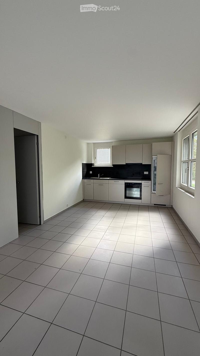 Empty kitchen with tiled floor, white cabinets, sink, oven, and refrigerator.