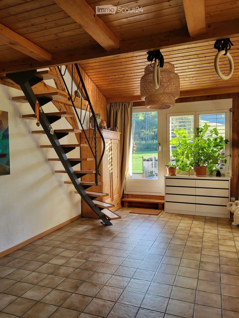 Cozy hallway with wooden ceiling, staircase, cabinet, potted plants, and a bench near the window.