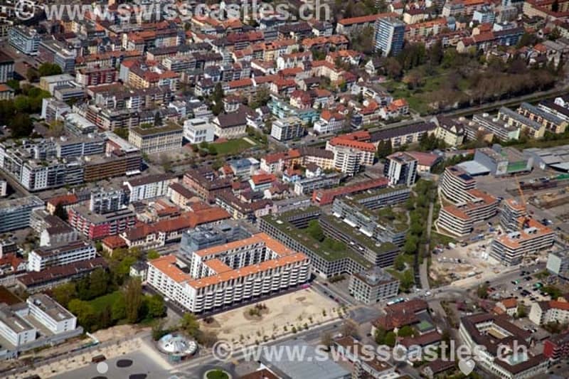 Aerial view of a dense urban area with numerous buildings, roads, and green spaces.