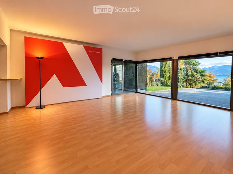 Empty room with wooden flooring, large windows, and a red and white wall design. No furniture or equipment present.