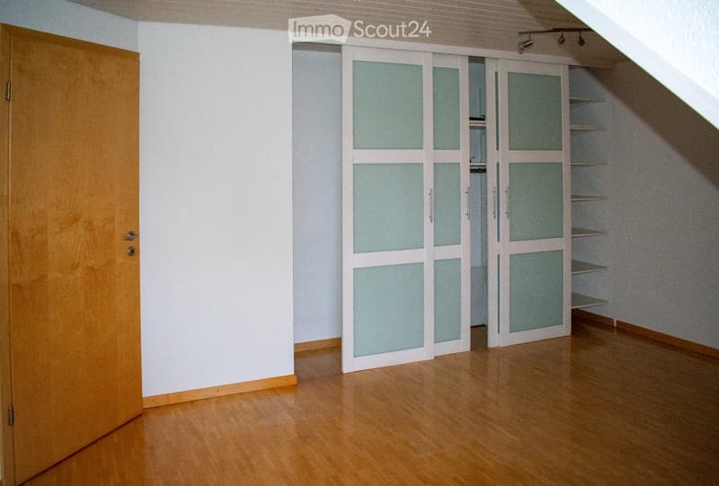Empty room with wooden flooring, white walls, and built-in closet with glass doors. No furniture or personal items present.