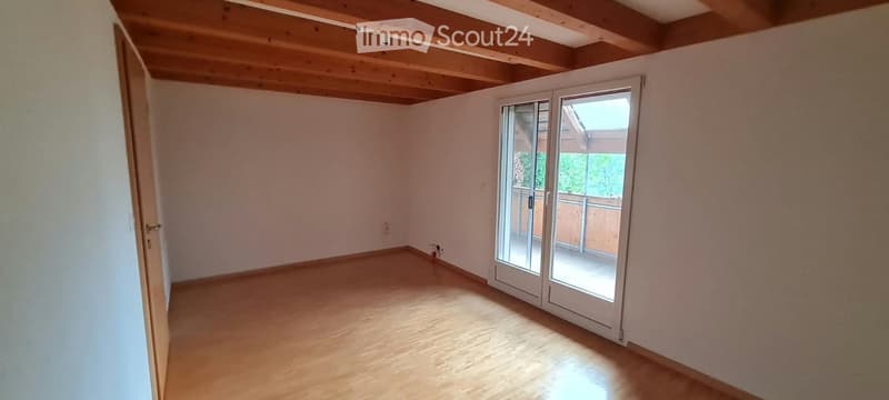Empty room with wooden flooring, white walls, and a large sliding glass door leading to a balcony.