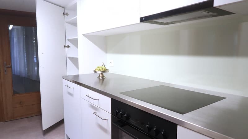 Modern kitchen with white cabinets, stainless steel appliances, and a sleek countertop.