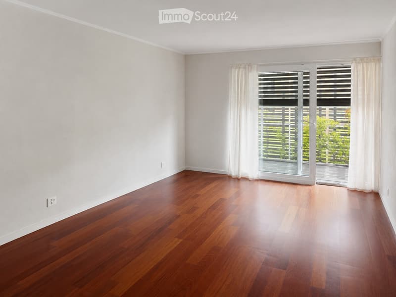 Empty room with wooden flooring, white walls, and large sliding glass doors leading to a balcony.