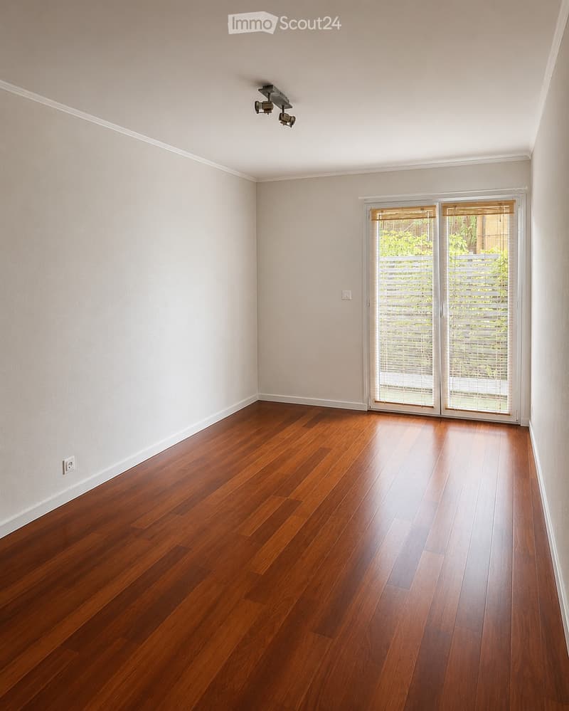 Empty room with wooden flooring, white walls, and a sliding glass door leading to an outdoor area.